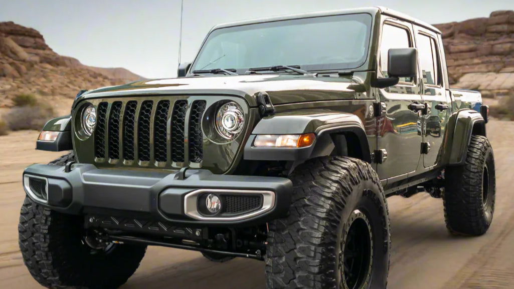 Green Jeep Gladiator with aftermarket headlights on a dirt road